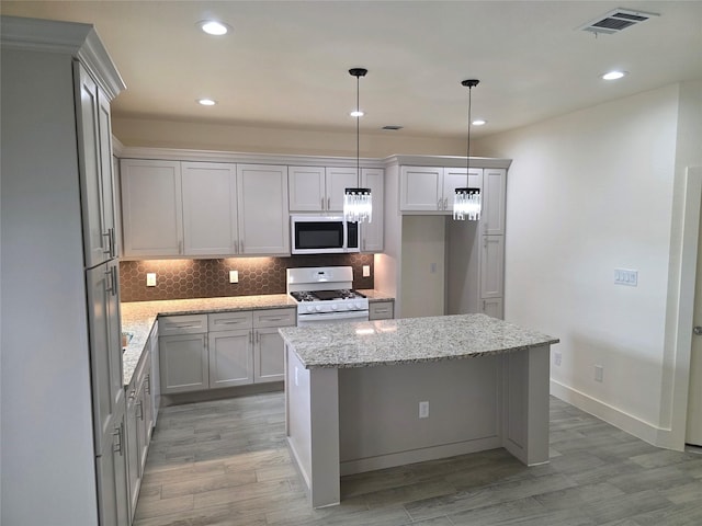 2140 De Soto St, Houston, TX 77091 - kitchen with tasteful backsplash, light stone counters, white range with gas cooktop, a center island, and visible vents