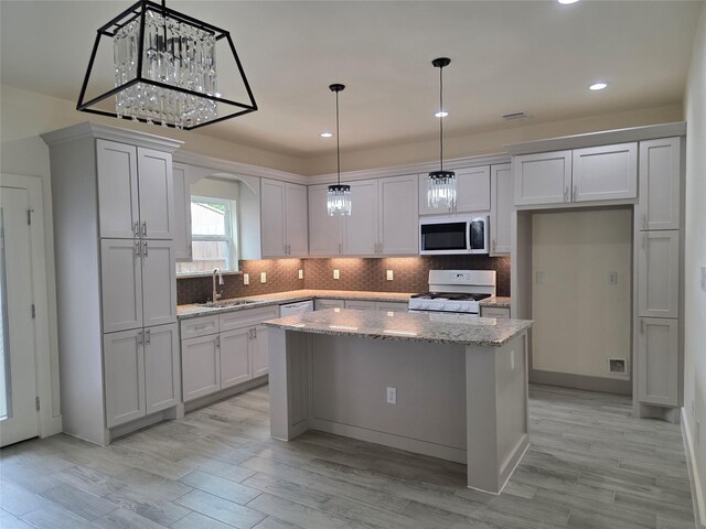 2140 De Soto St, Houston, TX 77091 - kitchen with arched walkways, white appliances, light wood-style flooring, a kitchen island, and a sink