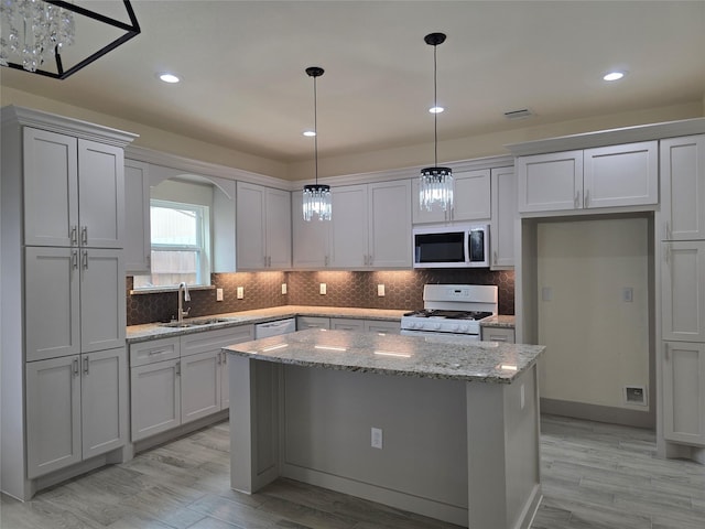 2140 De Soto St, Houston, TX 77091 - kitchen featuring arched walkways, white appliances, decorative backsplash, a kitchen island, and a sink