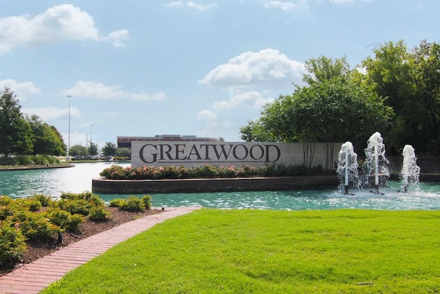 community sign with a water view and a yard