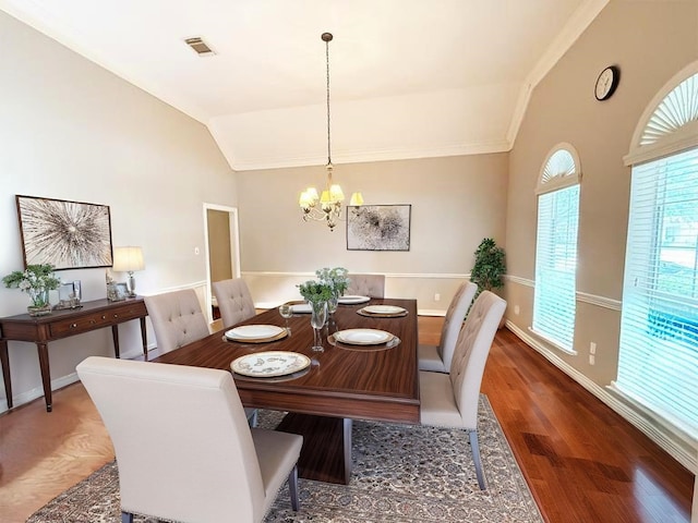 dining area with visible vents, a notable chandelier, wood finished floors, and vaulted ceiling