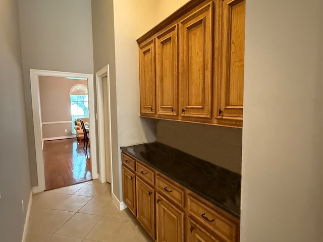 interior space with backsplash, baseboards, light tile patterned floors, and a high ceiling