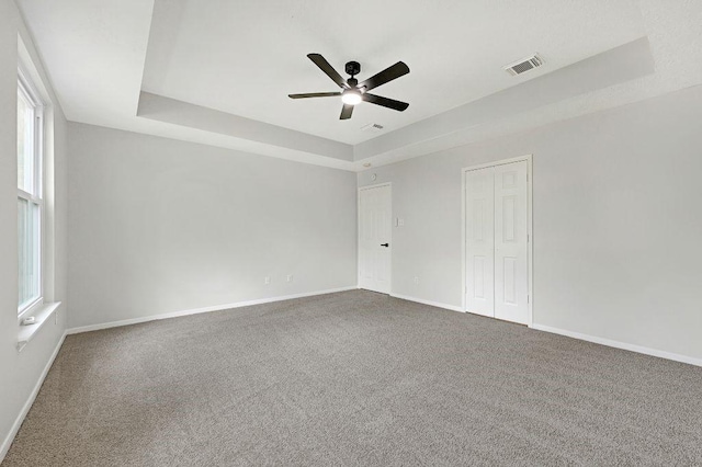 empty room with visible vents, carpet, and a raised ceiling