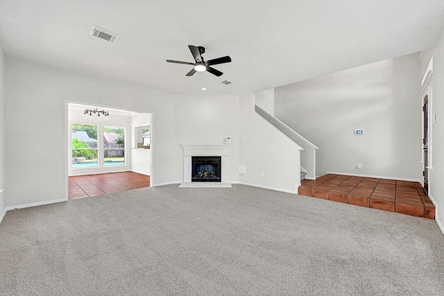 unfurnished living room featuring a ceiling fan, stairs, carpet, tile patterned flooring, and visible vents