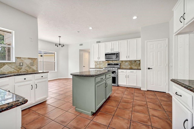 kitchen with backsplash, appliances with stainless steel finishes, visible vents, and white cabinets