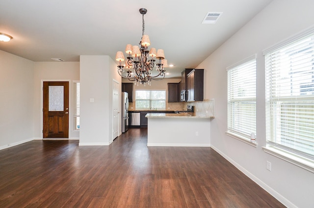 24430 Vittorio Wood Ln, Katy, TX 77493 - kitchen with appliances with stainless steel finishes, a chandelier, dark brown cabinetry, decorative backsplash, and dark wood-style flooring