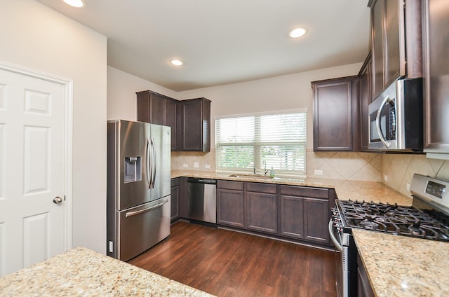 24430 Vittorio Wood Ln, Katy, TX 77493 - kitchen featuring appliances with stainless steel finishes, dark wood-type flooring, dark brown cabinetry, a sink, and light stone counters