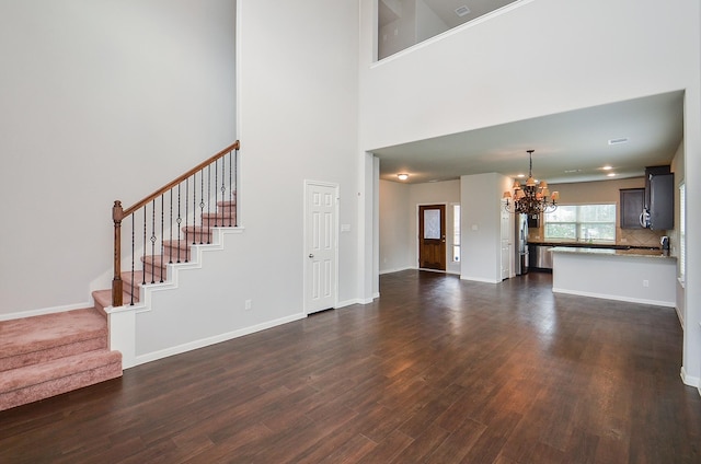 24430 Vittorio Wood Ln, Katy, TX 77493 - unfurnished living room featuring a chandelier, dark wood finished floors, stairs, baseboards, and a high ceiling