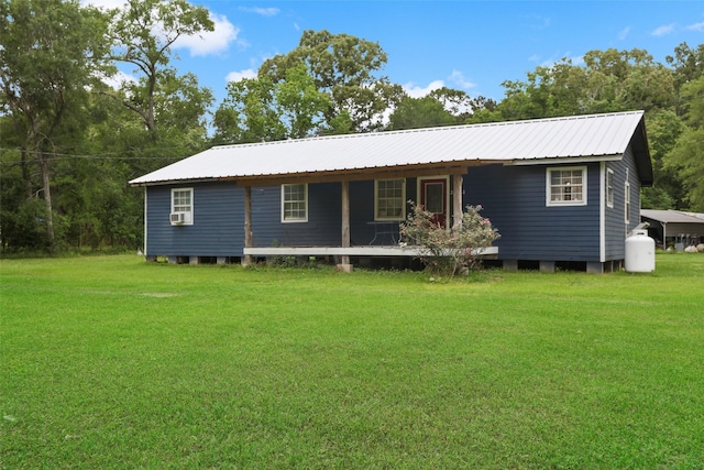 ranch-style home featuring covered porch, a front yard, cooling unit, and metal roof
