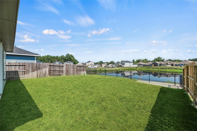 view of yard featuring a fenced backyard, a residential view, and a water view