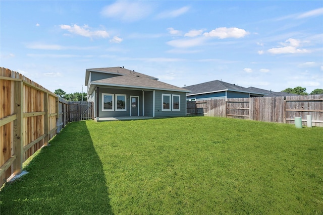 rear view of property featuring a fenced backyard, a patio area, a yard, and a shingled roof