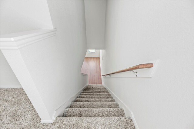 stairway with baseboards and carpet flooring