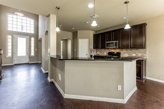 3713 Daisy Ln, Huntsville, TX 77340 - kitchen with arched walkways, dark brown cabinetry, stainless steel microwave, dark wood-type flooring, and visible vents
