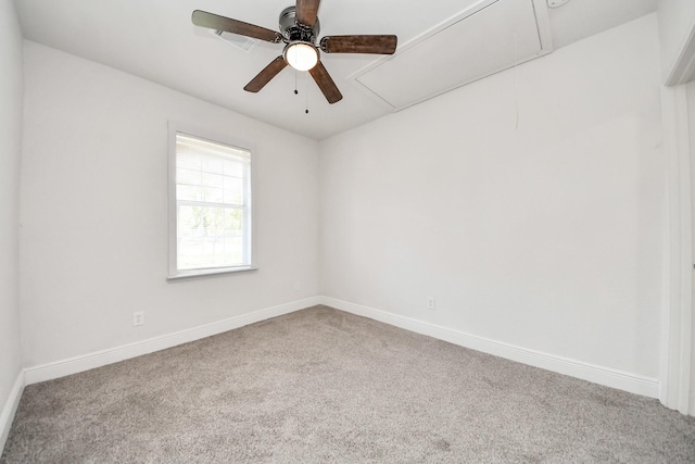 carpeted empty room featuring baseboards, a ceiling fan, and attic access