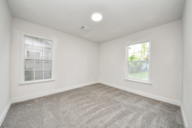 spare room with baseboards, carpet flooring, and visible vents