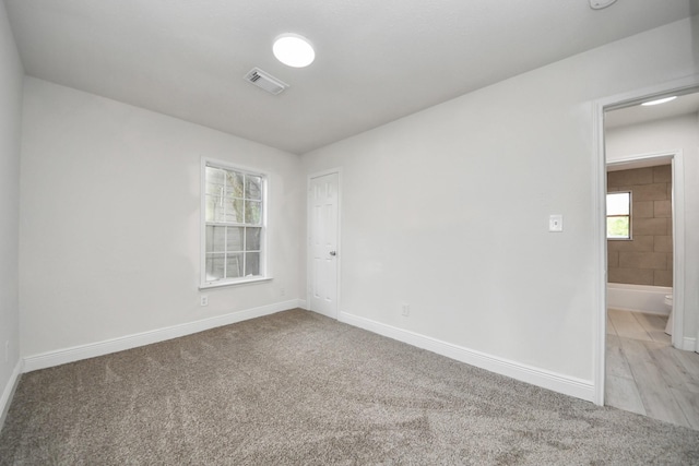 spare room featuring baseboards, visible vents, and carpet