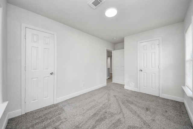 unfurnished bedroom featuring carpet floors, baseboards, and visible vents