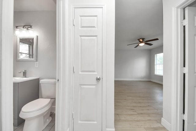 bathroom featuring ceiling fan, vanity, toilet, baseboards, and wood finished floors