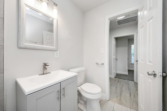 bathroom featuring vanity, baseboards, toilet, and visible vents