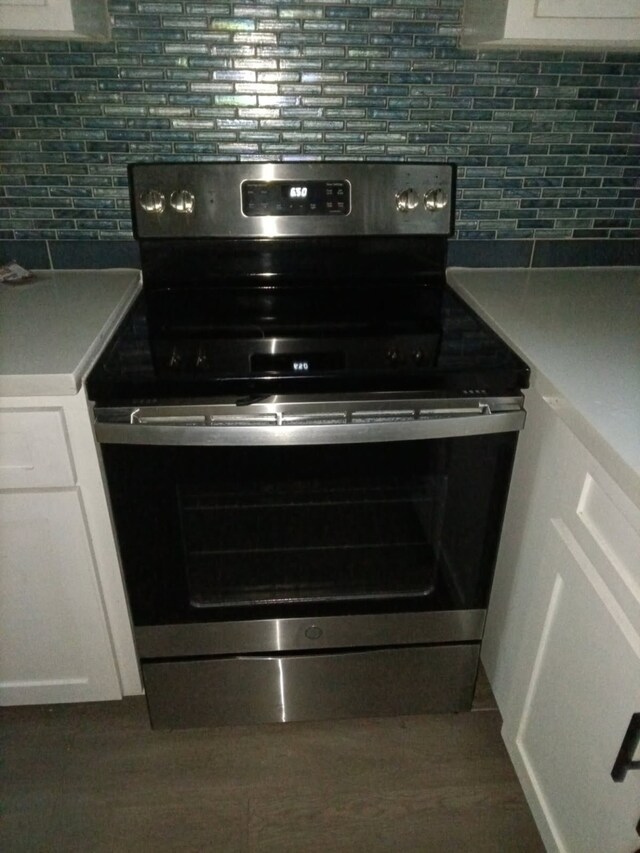 504 Cedar St, Sweeny, TX 77480 - kitchen view of stainless steel range with electric cooktop, tasteful backsplash, and white cabinetry