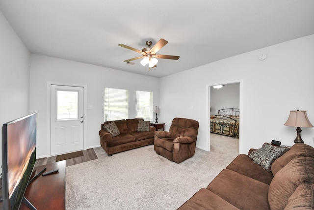 carpeted living room featuring a ceiling fan and baseboards