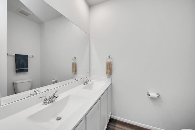 bathroom with toilet, a sink, visible vents, and baseboards