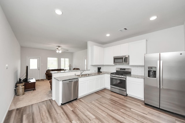 kitchen with light wood finished floors, stainless steel appliances, a sink, visible vents, and white cabinetry