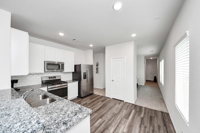 kitchen featuring visible vents, a sink, dark wood-type flooring, tasteful backsplash, and appliances with stainless steel finishes