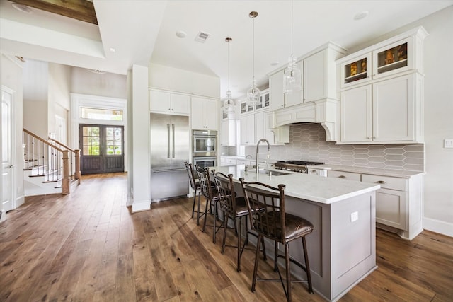 6605 Rolla St, Houston, TX 77055 - kitchen featuring appliances with stainless steel finishes, backsplash, dark wood-style flooring, a kitchen bar, and a sink