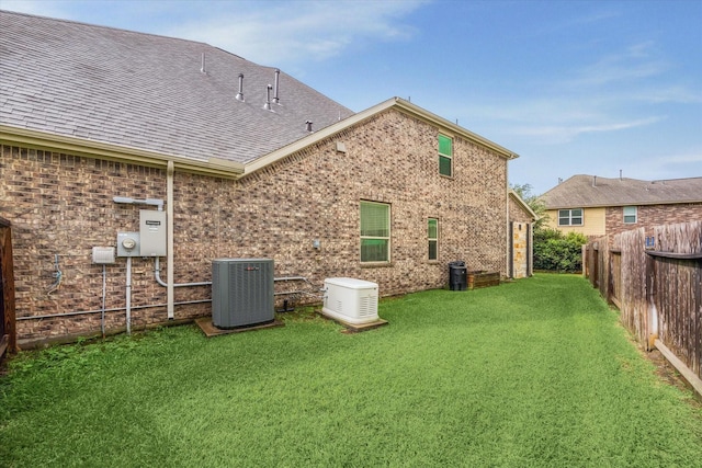 8207 Mesquite Hill Ln, Richmond, TX 77469 - rear view of property featuring roof with shingles, central AC, brick siding, a fenced backyard, and a yard