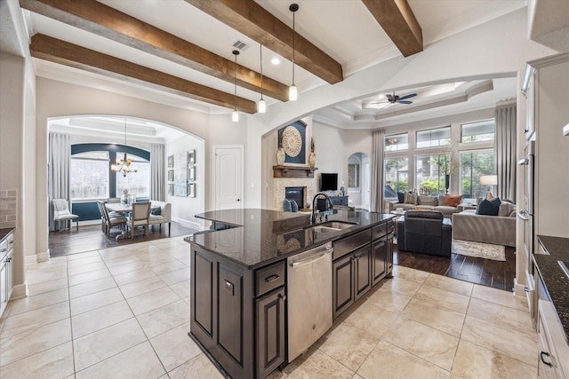 8207 Mesquite Hill Ln, Richmond, TX 77469 - kitchen with beamed ceiling, a stone fireplace, arched walkways, a sink, and appliances with stainless steel finishes