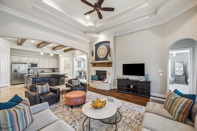 8207 Mesquite Hill Ln, Richmond, TX 77469 - living room featuring arched walkways, a ceiling fan, ornamental molding, and a stone fireplace