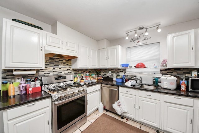 kitchen featuring tasteful backsplash, a sink, appliances with stainless steel finishes, white cabinets, and under cabinet range hood