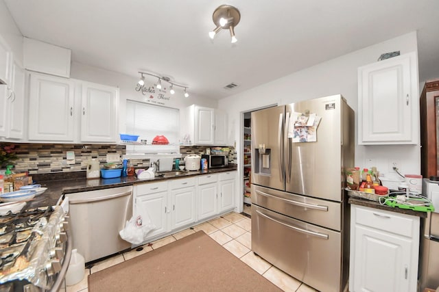 kitchen with white cabinets, dark countertops, decorative backsplash, and appliances with stainless steel finishes