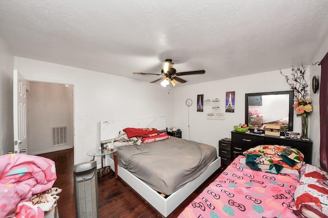bedroom featuring wood finished floors, visible vents, a textured ceiling, and a ceiling fan