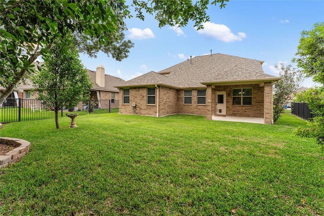 rear view of house featuring a fenced backyard, a yard, a patio area, and a shingled roof