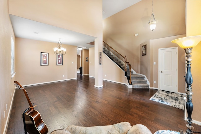 entryway featuring baseboards, a high ceiling, hardwood / wood-style flooring, and a notable chandelier