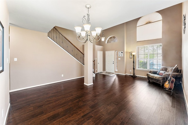 entryway featuring hardwood / wood-style floors, a high ceiling, baseboards, and an inviting chandelier