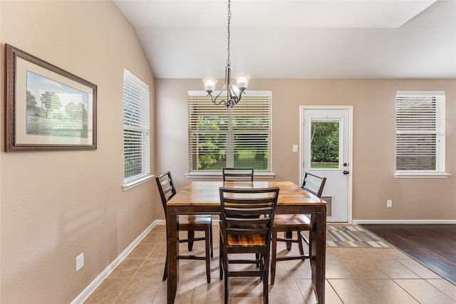 dining area featuring lofted ceiling, baseboards, a notable chandelier, and light tile patterned floors