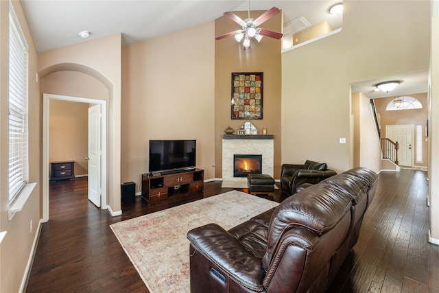 living room featuring a fireplace, dark wood finished floors, a ceiling fan, and high vaulted ceiling
