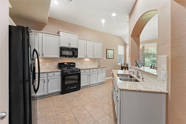 kitchen with arched walkways, a sink, decorative backsplash, black appliances, and light tile patterned floors