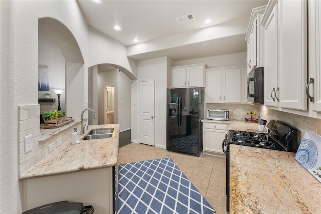 18823 Cove Mill Ln, Cypress, TX 77433 - kitchen featuring black appliances, light tile patterned floors, backsplash, arched walkways, and white cabinetry