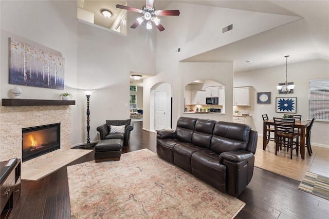 18823 Cove Mill Ln, Cypress, TX 77433 - living room featuring a ceiling fan, a stone fireplace, dark wood-type flooring, high vaulted ceiling, and arched walkways