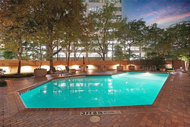 community pool with a patio and fence