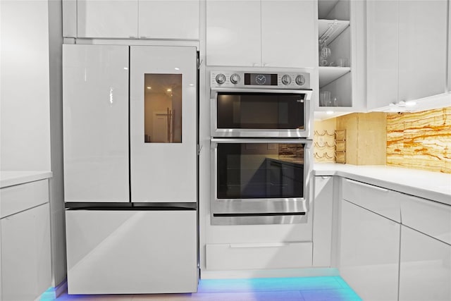 kitchen with white cabinets, stainless steel double oven, light countertops, modern cabinets, and refrigerator