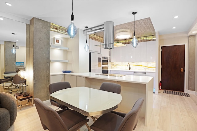 kitchen featuring light countertops, modern cabinets, hanging light fixtures, appliances with stainless steel finishes, and white cabinetry