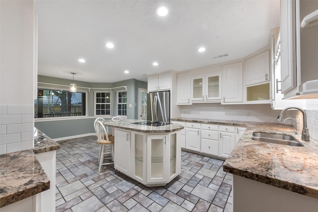 302 Hickory Ridge Dr, El Lago, TX 77586 - kitchen with stone finish floor, white cabinetry, glass insert cabinets, a sink, and freestanding refrigerator