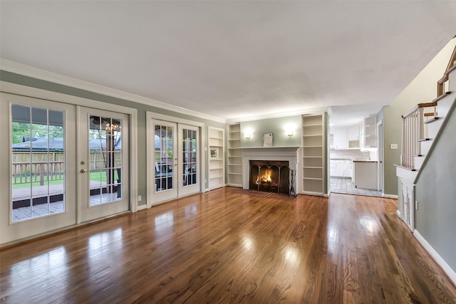 302 Hickory Ridge Dr, El Lago, TX 77586 - unfurnished living room with wood finished floors, ornamental molding, built in shelves, french doors, and a fireplace with flush hearth