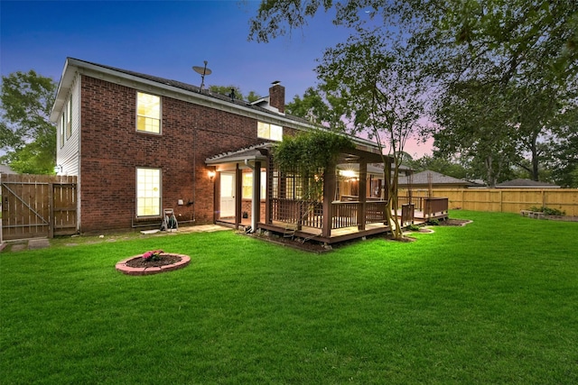 302 Hickory Ridge Dr, El Lago, TX 77586 - back of property at dusk with a chimney, a deck, a fenced backyard, a yard, and brick siding