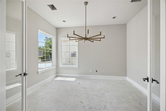 unfurnished dining area featuring concrete flooring, baseboards, french doors, and an inviting chandelier